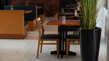 Un restaurante moderno con mobiliario de madera, una pantalla de televisión grande y una planta en maceta.
