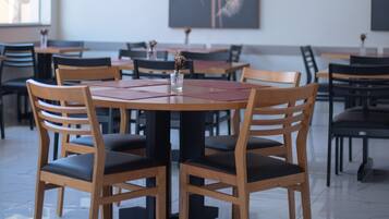 Un comedor con mesas y sillas de madera, un jarrón con flores y obras de arte en las paredes.