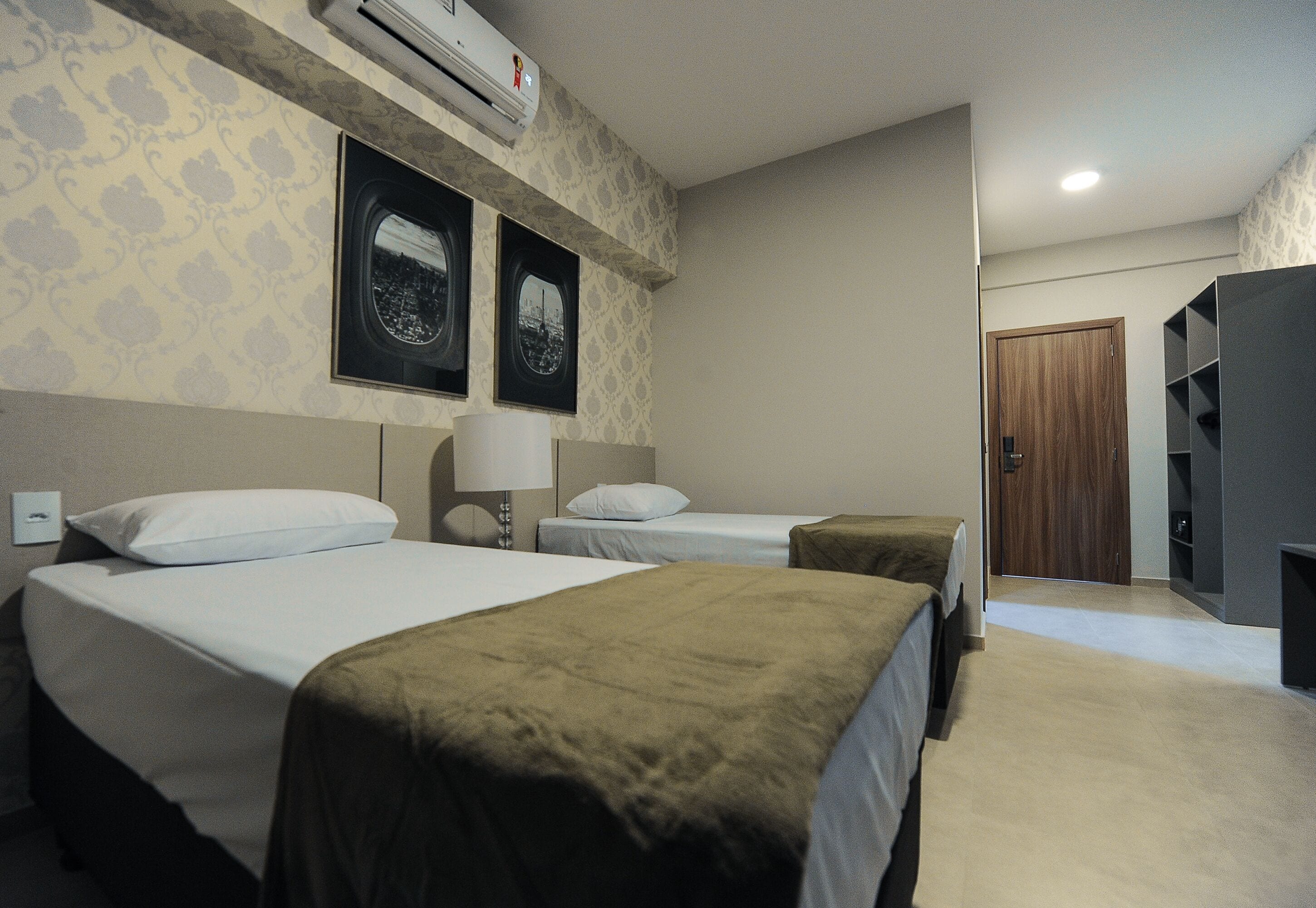 A hotel room with two beds, a wardrobe, and a mirror.