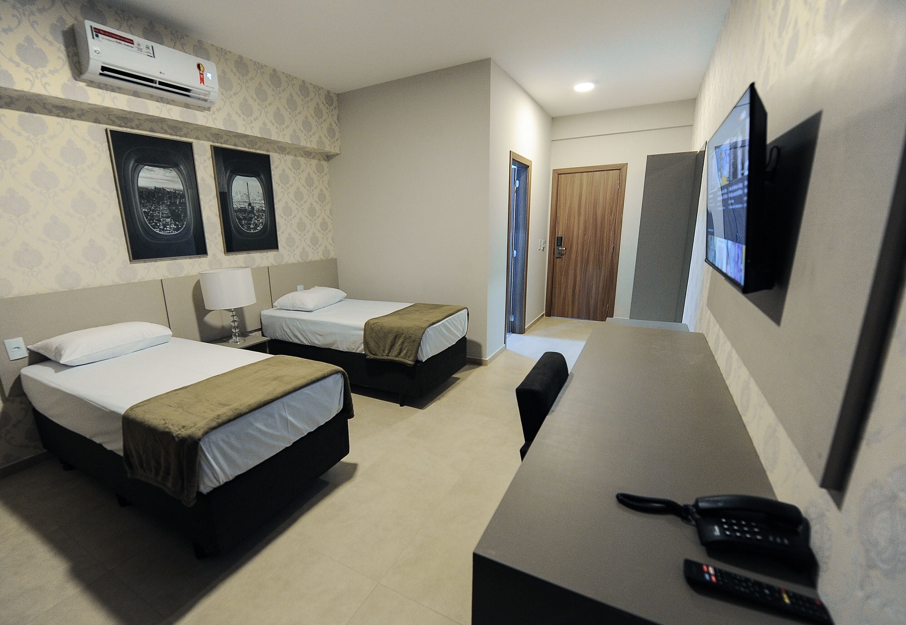 Habitación de hotel con dos camas, un escritorio, teléfono, televisor y aire acondicionado.