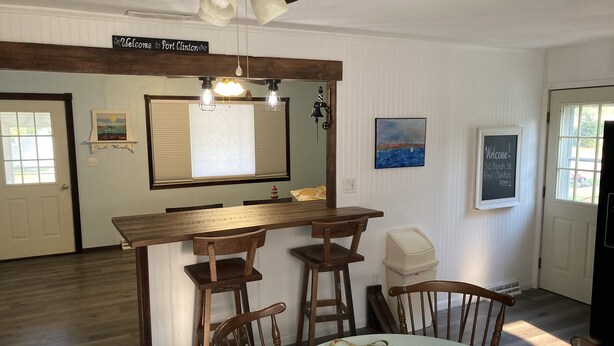 Een eethoek met een houten tafel en stoelen, een bar en een plafondventilator.