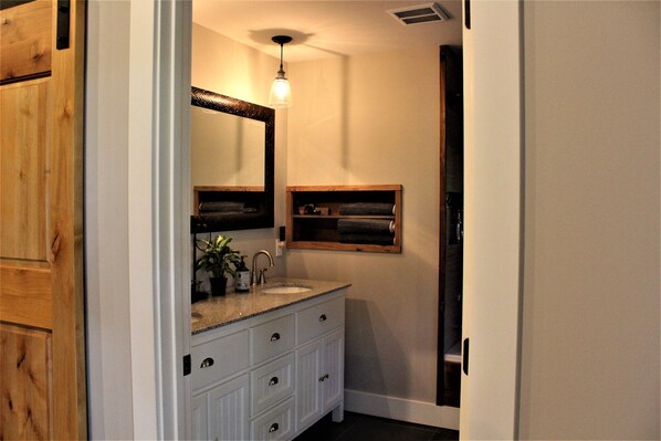A bathroom with a wooden vanity, a large mirror, a sink, and a towel rack.