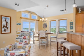 Una cocina con mesa de comedor, sillas, barra y vistas al exterior.