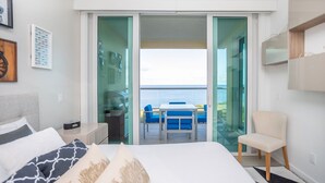 Une chambre d’hôtel avec un lit, un bureau, une chaise et un balcon donnant sur la mer.