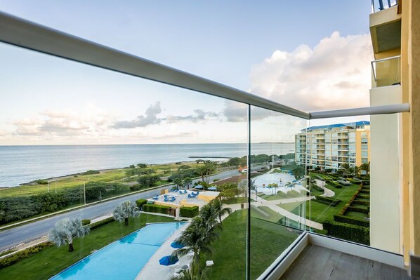 Un balcón con vistas a una piscina, un campo de golf y un edificio de hotel.