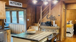 A rustic kitchen with a sign reading "KITCHEN" and a coffee bar sign.
