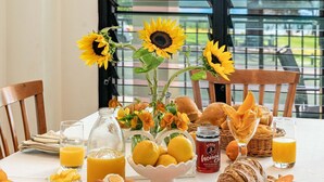 Une table de petit-déjeuner avec des tournesols, du pain, des oranges, du miel et du jus.