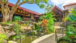 Un resort tropical con un estanque, senderos de piedra y abundante vegetación.
