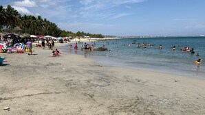 Ein Strand mit Menschen, die schwimmen und am Ufer entlanggehen.