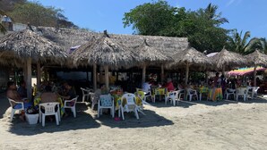 Ein Restaurant direkt am Strand mit reetgedeckten Dächern und Terrassensitzplätzen.