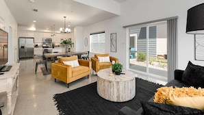 A spacious living area with a large round coffee table, two sofas, and a dining area with a kitchen in the background. - Gorgeous Townhome steps from the Brewery District! (Fort Collins)
