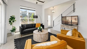 A modern living room with a black sofa, a round coffee table, and a yellow armchair. - Gorgeous Townhome steps from the Brewery District! (Fort Collins)
