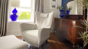 A room with a window, a chair, a dresser, and a mirror. - @The Clock (Westport)