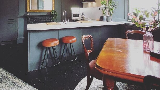 A modern kitchen with a central island, bar stools, a dining table, and a large window. - @The Clock (Westport)