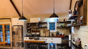 A kitchen with a central island, stainless steel appliances, and hanging pendant lights. - Quaint Little Cabin with a view. (Abbeville)