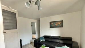 Een moderne woonkamer met een zwarte leren bank, een witte salontafel en een grijze plafondlamp.