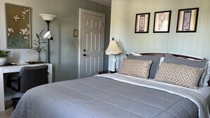 A neatly arranged bedroom with a bed, desk, and chair, a door, and three framed pictures on the wall. - Private Room on Serene Property in Hilo (Hilo)