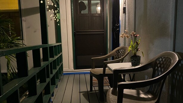A wooden deck with a table and chairs, a potted plant, and string lights. - Private Room on Serene Property in Hilo (Hilo)