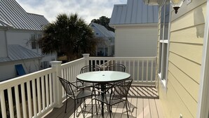 Een overdekt terras met een ronde tafel en stoelen, omringd door een witte balustrade.