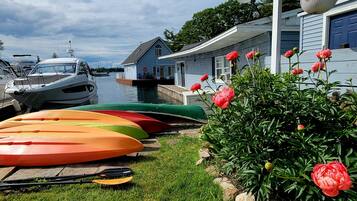 A dock with kayaks and a house with a blue door.