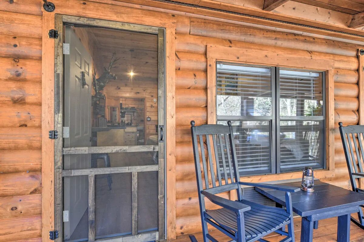 A wooden cabin with a sliding glass door, a window with blinds, and a table with two chairs.