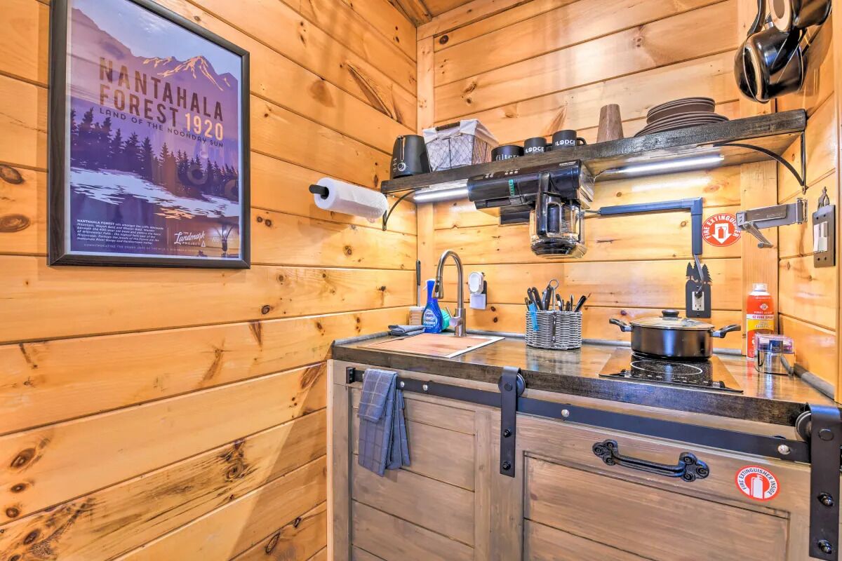 Cocina de cabaña de madera con un cartel de Nantaihala Forest, una estufa, un lavamanos y varios utensilios de cocina.