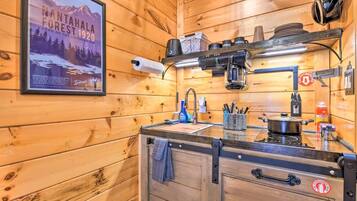 Cocina de cabaña de madera con un cartel de Nantaihala Forest, una estufa, un lavamanos y varios utensilios de cocina.