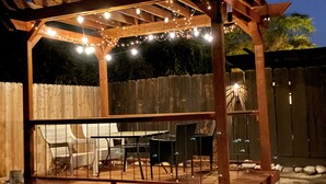 A wooden pergola with string lights, outdoor seating, and a wooden deck with rocks. - Sequoia Escape . Close to The  Springville Ranch Venue & Sequoia Nat. Park. (Springville)