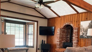 A cozy living room with a fireplace, wooden ceiling beams, a flat-screen TV, and a comfortable sofa. - Sequoia Escape . Close to The  Springville Ranch Venue & Sequoia Nat. Park. (Springville)