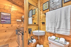 Baño de cabaña de madera con lavabo, inodoro y espejo.