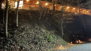 A wooden building with multiple illuminated windows and a staircase leading up to a covered area. - The Lodge Nantahala River<br>Bryson city, Nc. Suite #2<br>The Nantahala , Bryson city (Bryson City)