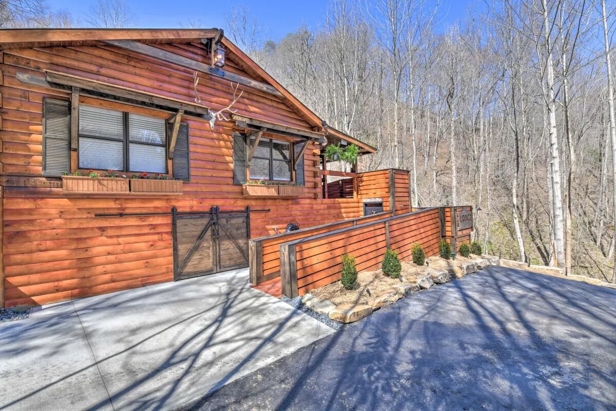 A log cabin with a porch, windows, and a small garden area.