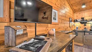 Ein Holzblock-Interieur mit großem Fernseher, Kamin, Küchenbereich und Vorschlagsbox.