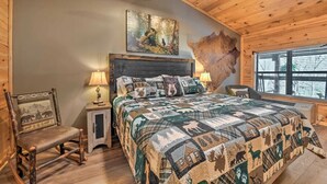 Ein gemütliches Schlafzimmer mit einem großen Bett, einem Holz-Kopfteil, rustikalen Wandbildern und einem Fenster mit Blick.
