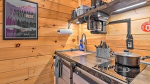 Ein Holzblockhaus-Innenraum mit Küchenbereich, inklusive Herd, Spüle und verschiedenen Küchenutensilien.