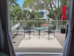 Una terraza con una mesa y sillas, una hamaca y un paraguas rojo.