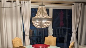 Ein Essbereich mit einem runden Tisch, vier Stühlen, einer Pendelleuchte und Blick nach draußen durch ein Fenster.