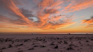 Ein Strand mit weitem Sandbereich und freiem Blick auf den Ozean.