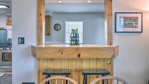 A kitchen with wooden bar stools, a coffee machine, and a clock on the wall. - Watkins Glen Lakeview Cottage w/ Waterfall! (Watkins Glen)