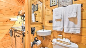 A wooden cabin bathroom with a sink, toilet, and towel rack.
