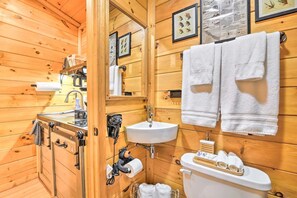 Ein Badezimmer einer Holzhütte mit Waschbecken, Toilette und Handtuchhalter.