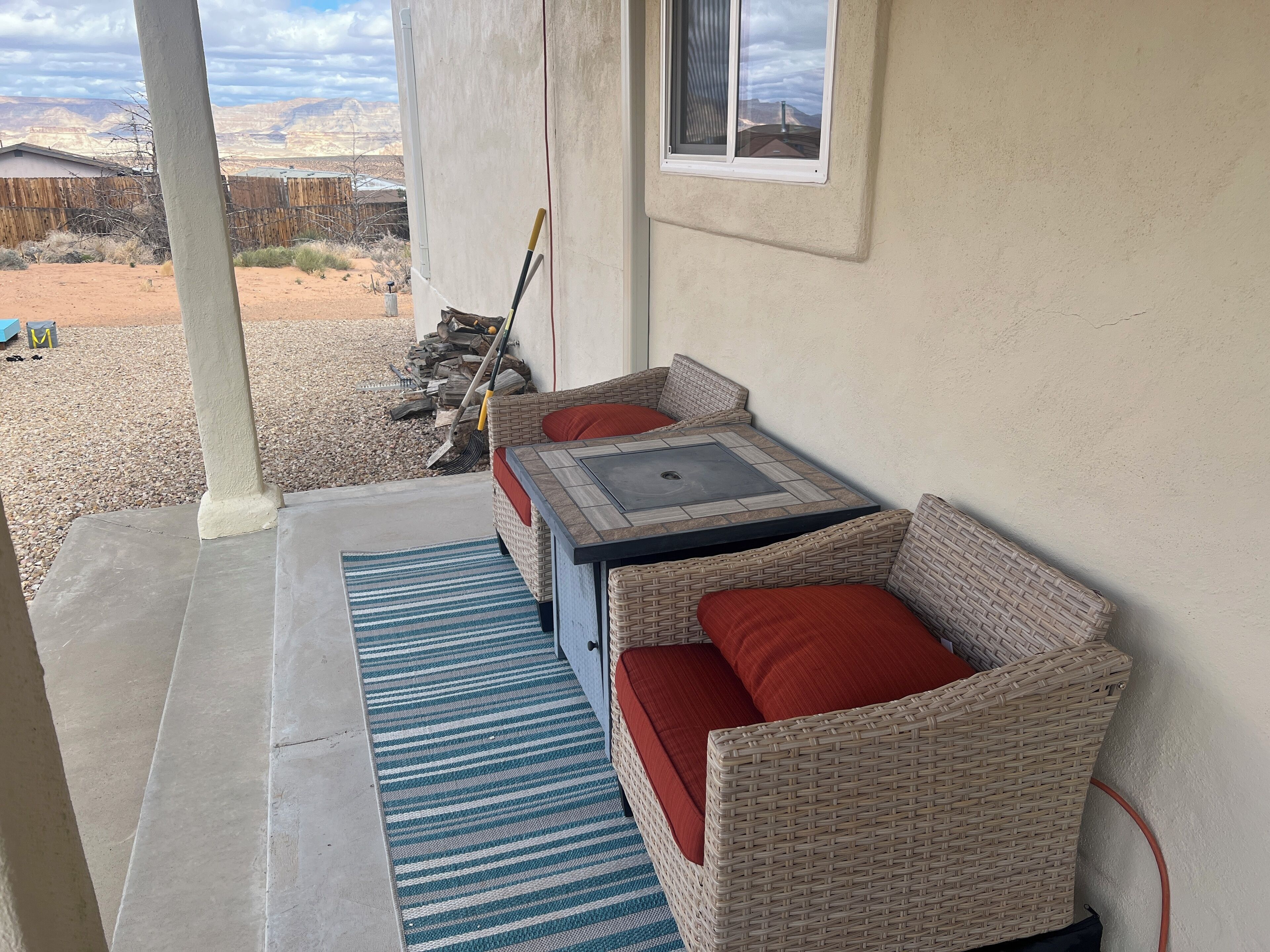 A covered patio area with wicker furniture and a view of the desert landscape.