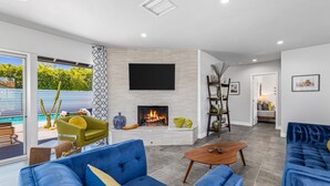 Ein modernes Wohnzimmer mit Kamin, blauen Sofas, einem Couchtisch und einem an der Wand befestigten Fernseher.