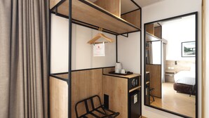 A compact hotel room with a wooden desk, a black chair, a mirror, and a view of a bedroom with a bed and a nightstand. - Casa Andina Standard Benavides (Lima)