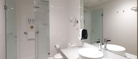 A modern bathroom with a glass-enclosed shower, a white sink, and a large mirror.