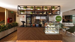 A modern cafe with a wooden counter, a glass display case with pastries, and a sign reading "sama". - Casa Andina Standard Benavides (Lima)