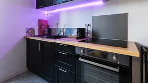 Une cuisine moderne avec des meubles de couleur noire, un plan de travail en bois, un four encastré et une machine à café.
