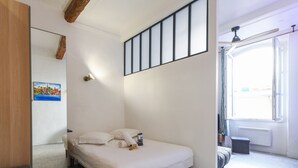 Une chambre à coucher avec un lit, une fenêtre, un ventilateur de plafond et un tableau accroché au mur.