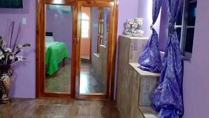 Een kamer met een houten deur die naar een andere kamer leidt, een betegelde vloer en een paarse muur.