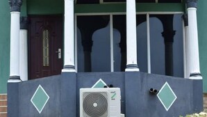 Een gebouw met een donkerbruine deur, witte zuilen en een groene gevel.